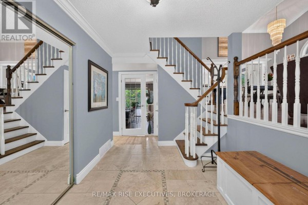 Spacious entryway with beige tile floors, a grand staircase, and mirrored closet doors. - 611 Rivermeade Avenue, Kingston