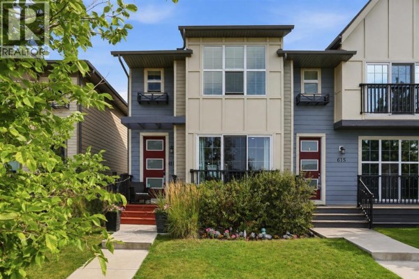 Grey kitchen with stainless steel appliances, island with white countertop, and backsplash. - 611 Walden Drive Se, Calgary