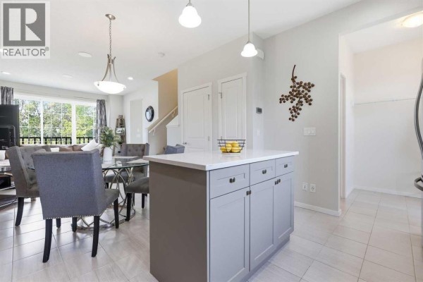 Open-concept living and dining area with a kitchen island, dining table, and view of the living room. - 611 Walden Drive Se, Calgary