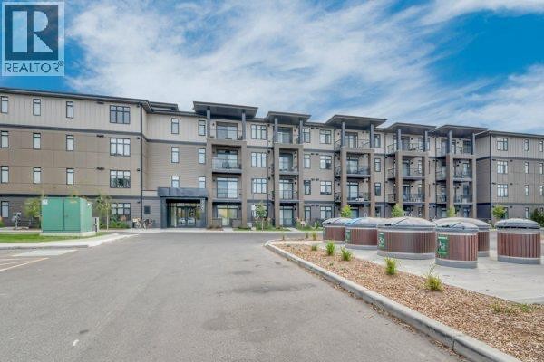 Wide view of a modern apartment building with multiple balconies and a large paved area in front. - 6112, 200 Seton Circle Se, Calgary