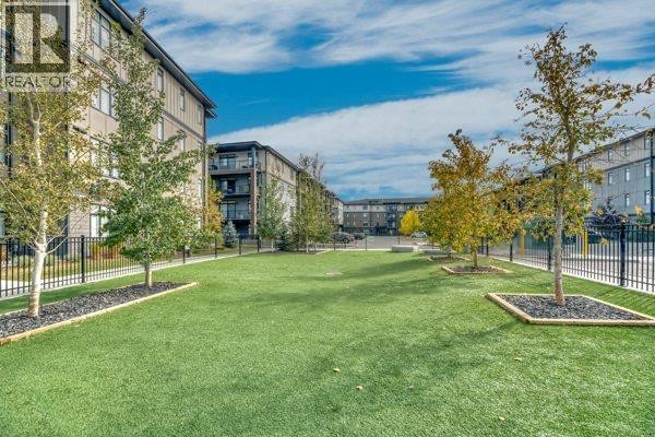 Open green space with artificial turf, surrounded by apartment buildings and trees in autumn colors. - 6112, 200 Seton Circle Se, Calgary