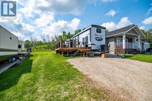 View of RVs and houses on a sunny day with a blue sky and white clouds. - 6112, 25054 South Pine Lake Road, Rural Red Deer County