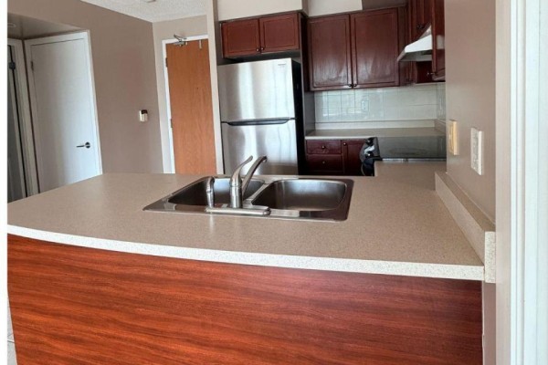 Kitchen island with double sink and wood base, adjacent to cabinets and appliances. - 612 - 219 Fort York Boulevard S, Toronto