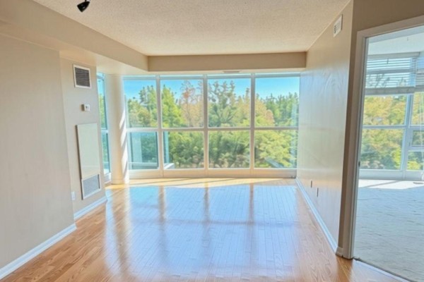 Living room with large windows offering a green tree-filled view and hardwood floors. - 612 - 219 Fort York Boulevard S, Toronto