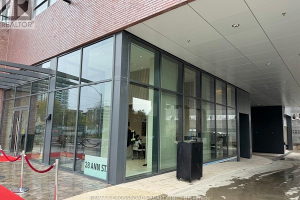 Glass entrance of a modern building with red carpet leading to the doors. - 612 - 28 Ann Street, Mississauga