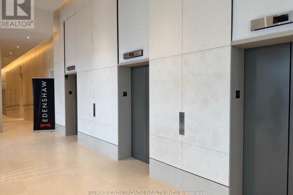 Three grey elevators with digital floor indicators in a bright lobby. - 612 - 28 Ann Street, Mississauga