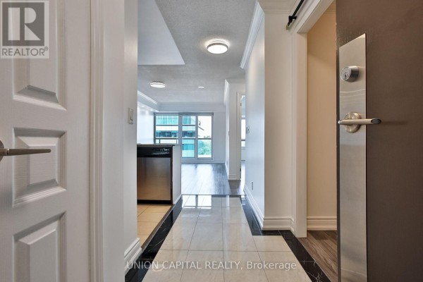 View into an apartment hallway showing doors, kitchen, and living area. - 612 - 32 Clegg Road, Markham