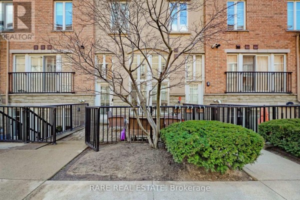Backyard patio area with bare tree, brick facade, and green bushes. - 612 - 38 Western Battery Road, Toronto