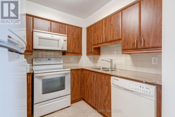 Kitchen with wood cabinets, white appliances including oven, microwave, and dishwasher. - 612 - 736 Spadina Avenue, Toronto