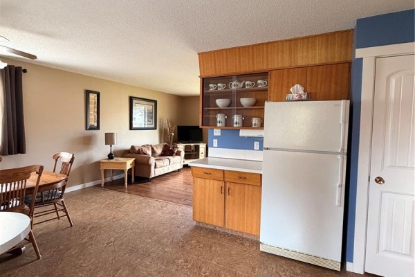 View from dining area into living room, showing kitchen cabinets and appliances. - 612 2nd Street W, Meadow Lake