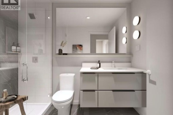 Bathroom with a walk-in shower, toilet, vanity with sink, and a large mirror with decorative lights. - 612 Elmwood Street, Coquitlam