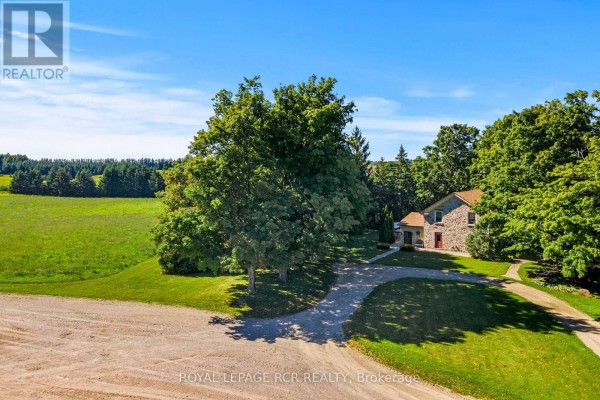 Side view of the stone farmhouse with a flagstone path leading to the red front door. - 6122 Ninth Line, Erin
