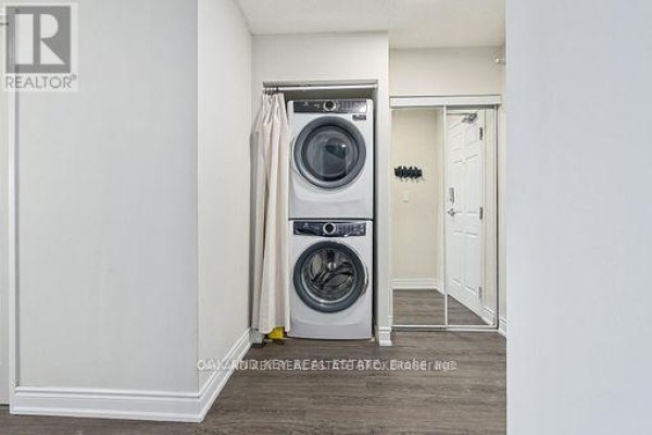 Stackable white front-loading washer and dryer in a closet with a mirrored sliding door. - 613 - 245 Davisville Avenue, Toronto