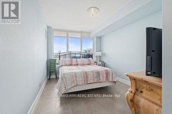 Bedroom with a queen-size bed, pale blue walls, and a large window with a city view. - 613 - 245 Davisville Avenue, Toronto