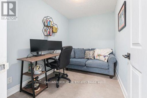 Home office with a desk, two monitors, an ergonomic chair, and a blue sofa. - 613 - 245 Davisville Avenue, Toronto