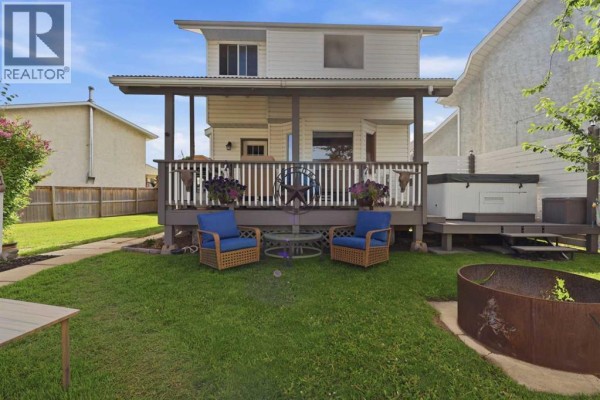 Deck with a white hot tub and grey wood decking, next to a white vinyl-sided house. - 6134 52 Street Close, Ponoka