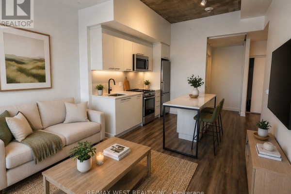 Open concept living area showing the sofa, kitchen island with stools, and view into hallway and another room. - 614 - 1808 St Clair Avenue W, Toronto