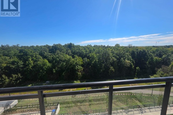 Balcony view of dense green trees and a clear blue sky with sunlight. - 614 - 740 Whitlock Avenue, Milton