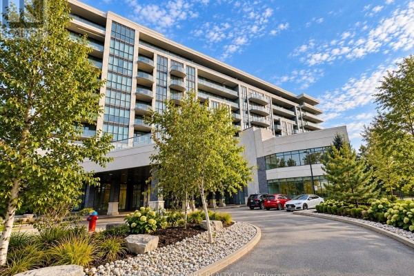 Curving driveway leading to the entrance of a modern apartment building with trees. - 614 - 7711 Green Vista Gate, Niagara Falls