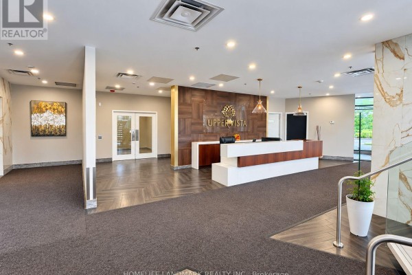 Building lobby with a reception desk, wood paneling, and marble accent walls. - 614 - 7711 Green Vista Gate, Niagara Falls