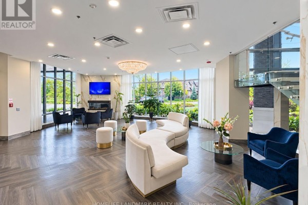 Lobby seating area with curved sofas, armchairs, fireplace, and large windows. - 614 - 7711 Green Vista Gate, Niagara Falls