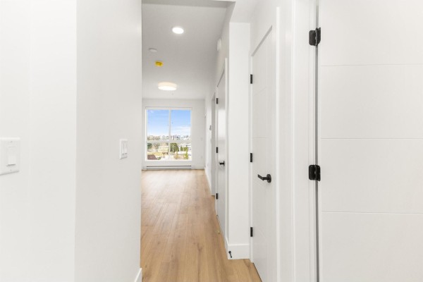 Interior hallway with light wood floors and multiple white doors. - 614 20769 Fraser Highway, Langley