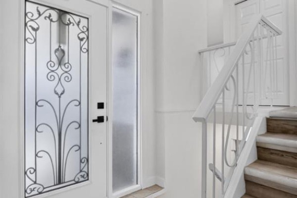 Close-up of a white front door with decorative glass panels and a frosted sidelight. - 614 Marlborough Way Ne, Calgary