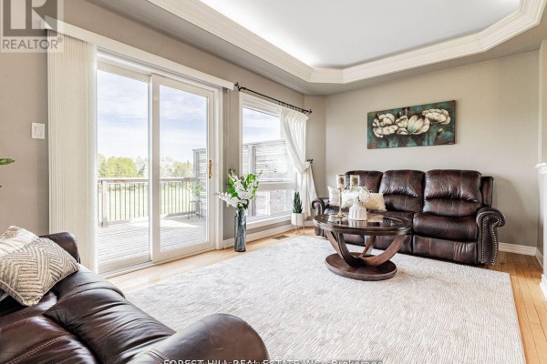 Living room with two sofas, a coffee table, and large windows overlooking a deck. - 614 Mcbean Avenue N, Newmarket