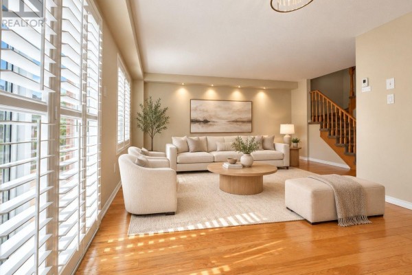 Living room with large windows, plantation shutters, hardwood floors, and neutral furniture. - 6143 Snowy Owl Crescent, Mississauga