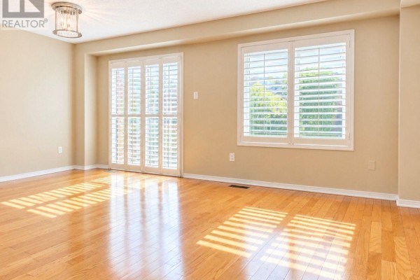 Interior view of a room with hardwood floors, sliding glass doors, and large windows. - 6143 Snowy Owl Crescent, Mississauga
