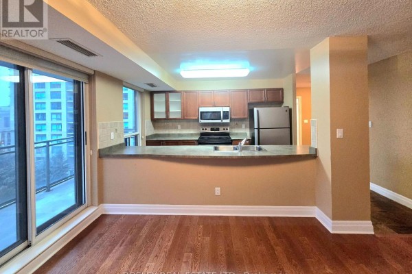 Kitchen with wood cabinets, granite countertops, stainless steel appliances, and a breakfast bar overlooking the living area. - 615 - 188 Doris Avenue, Toronto