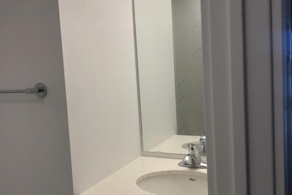 Bathroom vanity with a speckled countertop, white sink, and chrome faucet, reflected in a mirror. - 615 - 2433 Dufferin Street, Toronto