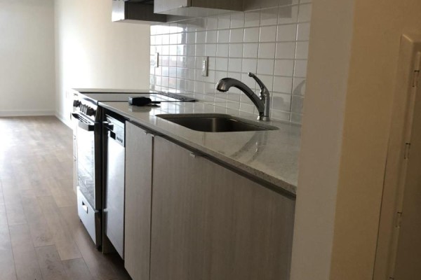 Kitchen counter with a stainless steel sink, faucet, dishwasher, stove, and white tiled backsplash. - 615 - 2433 Dufferin Street, Toronto