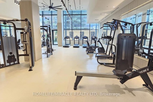 Spacious gym with cardio machines, weightlifting equipment, mirrors, and bright overhead lighting. - 615 - 28 Ann Street, Mississauga