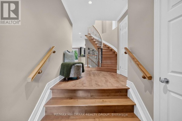 Interior foyer with hardwood floors, a curved staircase with wooden railings, and a bench. - 615 Aquaview Drive, Ottawa