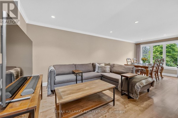 Living room with a sectional sofa, coffee table, and dining area with chairs. - 615 Aquaview Drive, Ottawa
