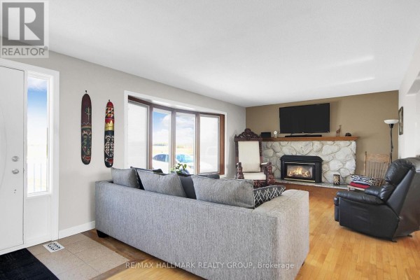 Living room with stone fireplace, bay window, and large sofa - 6151 Malakoff Road Ottawa