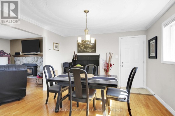 Dining room with dark wood table, chandelier, and view to living room with fireplace and TV - 6151 Malakoff Road Ottawa
