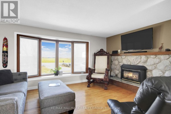 Living room with stone fireplace, bay window, and ornate chair - 6151 Malakoff Road Ottawa