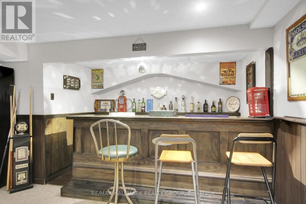 Basement bar with wood paneling, vintage gas pump, and bar stools - 6151 Malakoff Road Ottawa