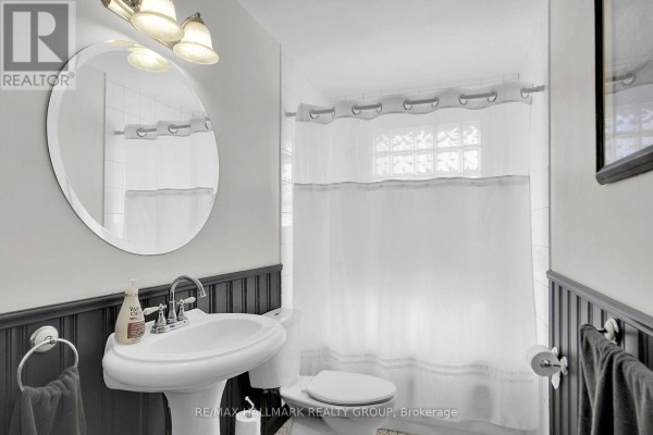 Bathroom with pedestal sink, round mirror, and shower curtain - 6151 Malakoff Road Ottawa