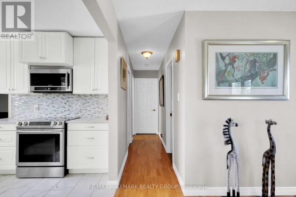Modern kitchen area and hallway with hardwood floors, framed art, and animal sculptures - 6151 Malakoff Road Ottawa