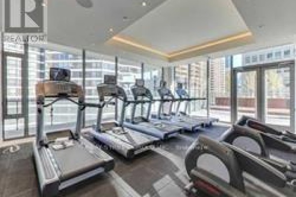 Gym with treadmills and elliptical machines, large windows overlooking city buildings. - 616 - 57 St Joseph Street, Toronto