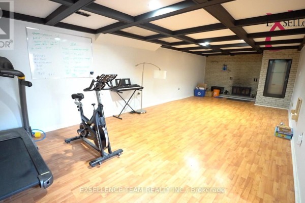 Finished basement with wood floors, exercise equipment, and brick fireplace with wood mantel. - 616 Surgenor Street W, Cornwall