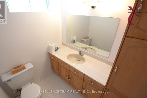 Powder room with white toilet, wood vanity, beige countertop, and large mirror. - 616 Surgenor Street W, Cornwall