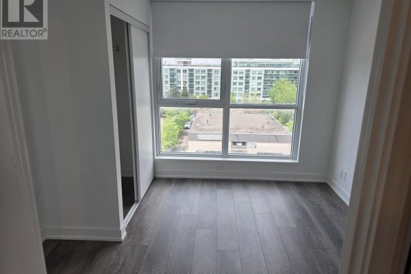 Bedroom with a large window and view of apartment buildings. - 617 - 20 Deans Drive, Toronto