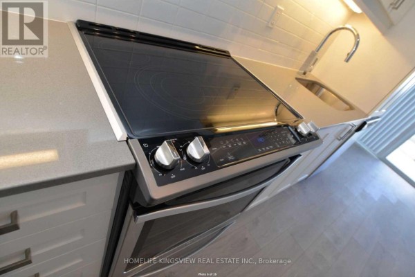 Close-up view of a stainless steel stove, grey countertop, and sink faucet. - 617 - 7895 Jane Street, Vaughan