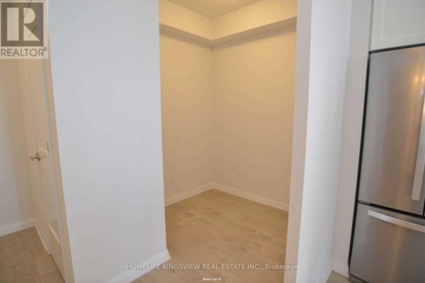 A small, empty room with white walls and light wood flooring off the kitchen. - 617 - 7895 Jane Street, Vaughan