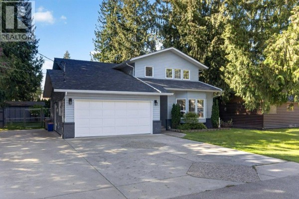 Side view of the light blue house showing the garage and grey siding accents. - 617 Pine Street, Sicamous