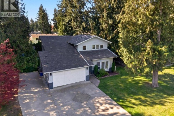 Overhead drone shot showing the house, driveway, green lawn, and surrounding trees. - 617 Pine Street, Sicamous